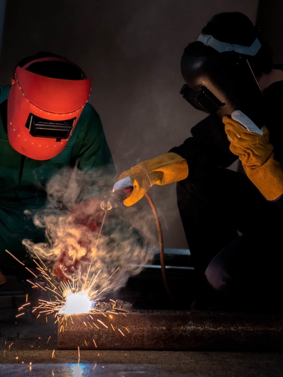 Workers welding, sparks fly. 