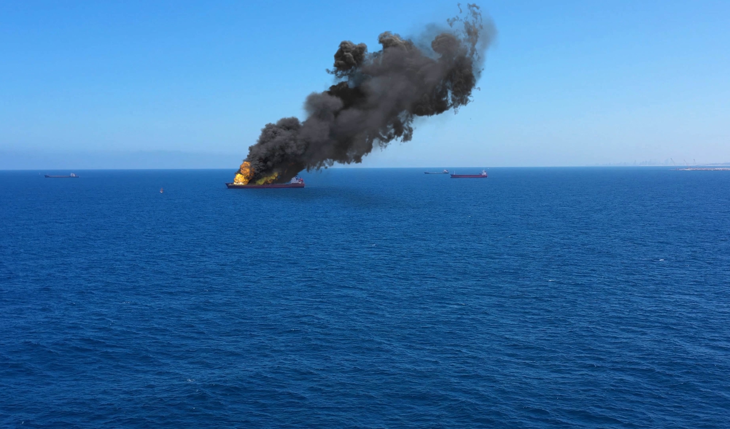 A cargo ship on fire out at sea.