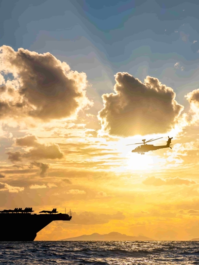 Defence ships and helecopter at sunset at sea